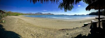Ubicación cercana a la playa, arena negra, sombrillas y toallas de playa