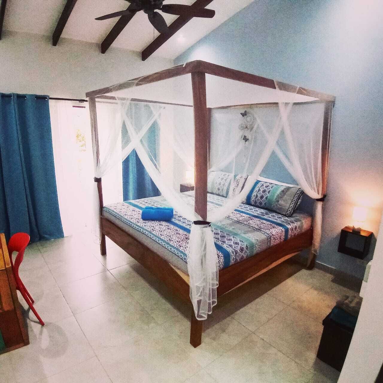 Un lit à baldaquin, une table de chevet avec une lampe et une vue sur le plafond de la pièce.
