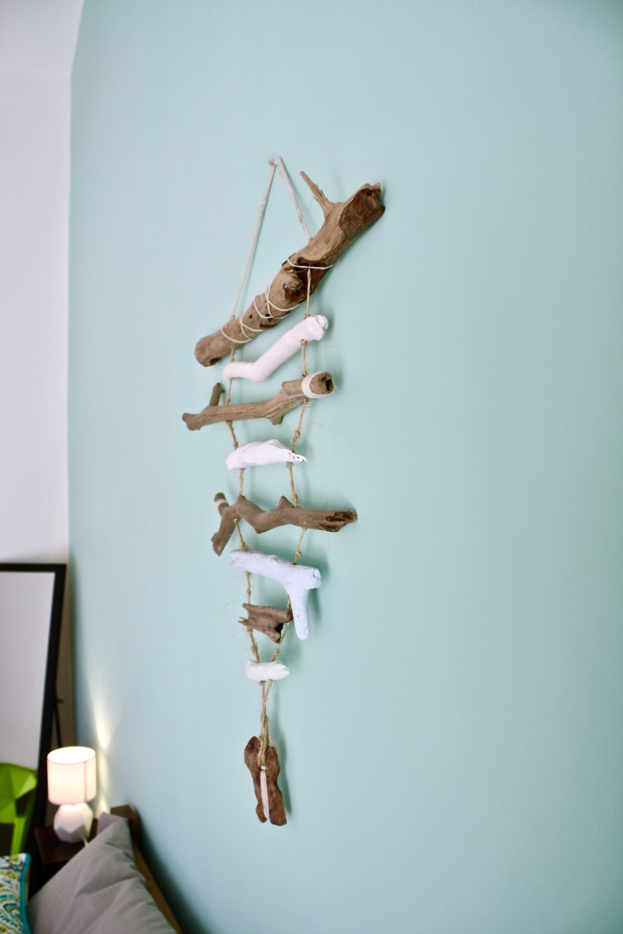 A wall with a wooden mobile hanging from it.