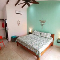Un dormitorio con cama, ventilador de techo, aire acondicionado, un atrapasueños y decoración de pared.