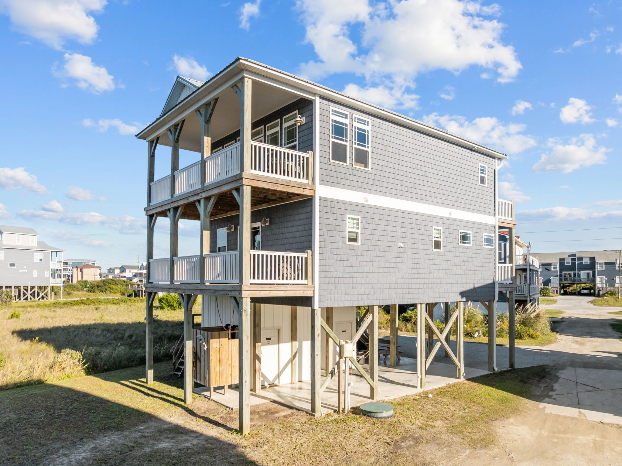 A two-story wooden house with a balcony on the upper floor, situated on stilts near the water.