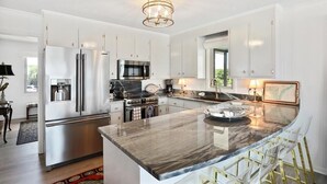A modern kitchen with stainless steel appliances, a marble island, and pendant lighting. - Discounted rates! The Edge of the Edge of America! (Folly Beach)