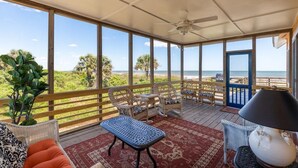 A covered outdoor area with wicker furniture, a red patterned rug, and a view of the beach. - Discounted rates! The Edge of the Edge of America! (Folly Beach)