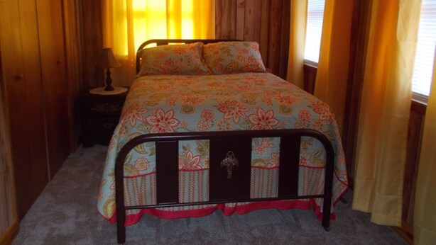 A bedroom with a wooden headboard, a floral bedspread, and a nightstand with a lamp. - Roomy Relaxing House Large Yard Stores Restaurants Trails Lake River Paved Drive (Abingdon)