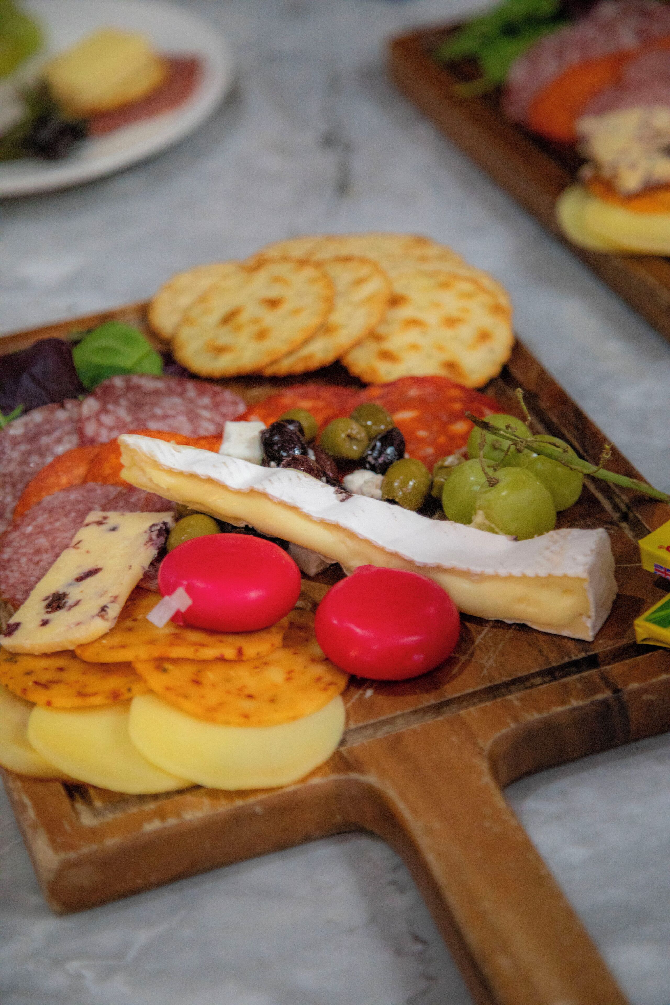 Una tabla de quesos y fiambres con diversos quesos, aceitunas y galletas.