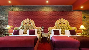 Quarto de hotel luxuoso com duas camas, cada uma com cabeceira dourada, roupa de cama vermelha e branca e tapete vermelho.