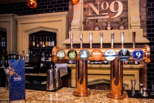 A bar with multiple taps, including brands like Budweiser, Mahou, and Guinness.