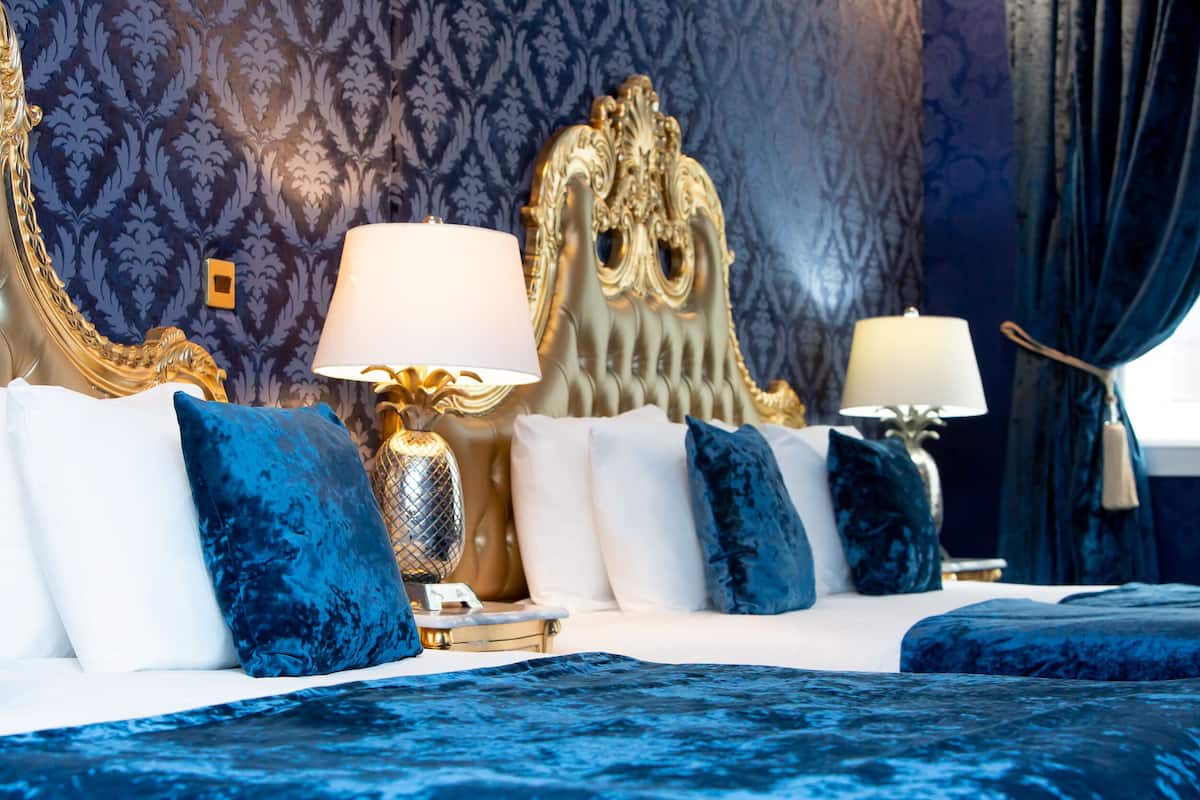 A luxurious bedroom with a large bed, ornate headboard, and two bedside lamps.