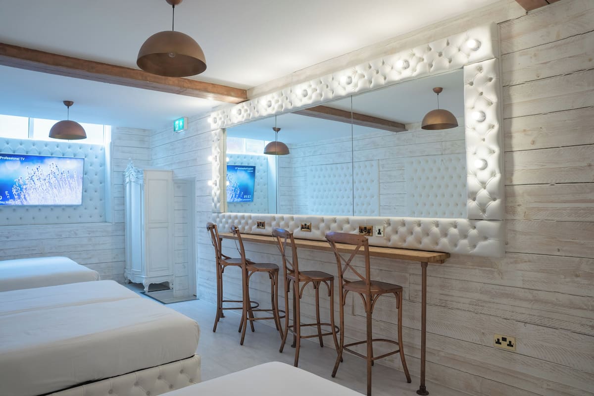 A room with a white cushioned sofa, a wooden bar with stools, and a large mirror with a decorative frame.