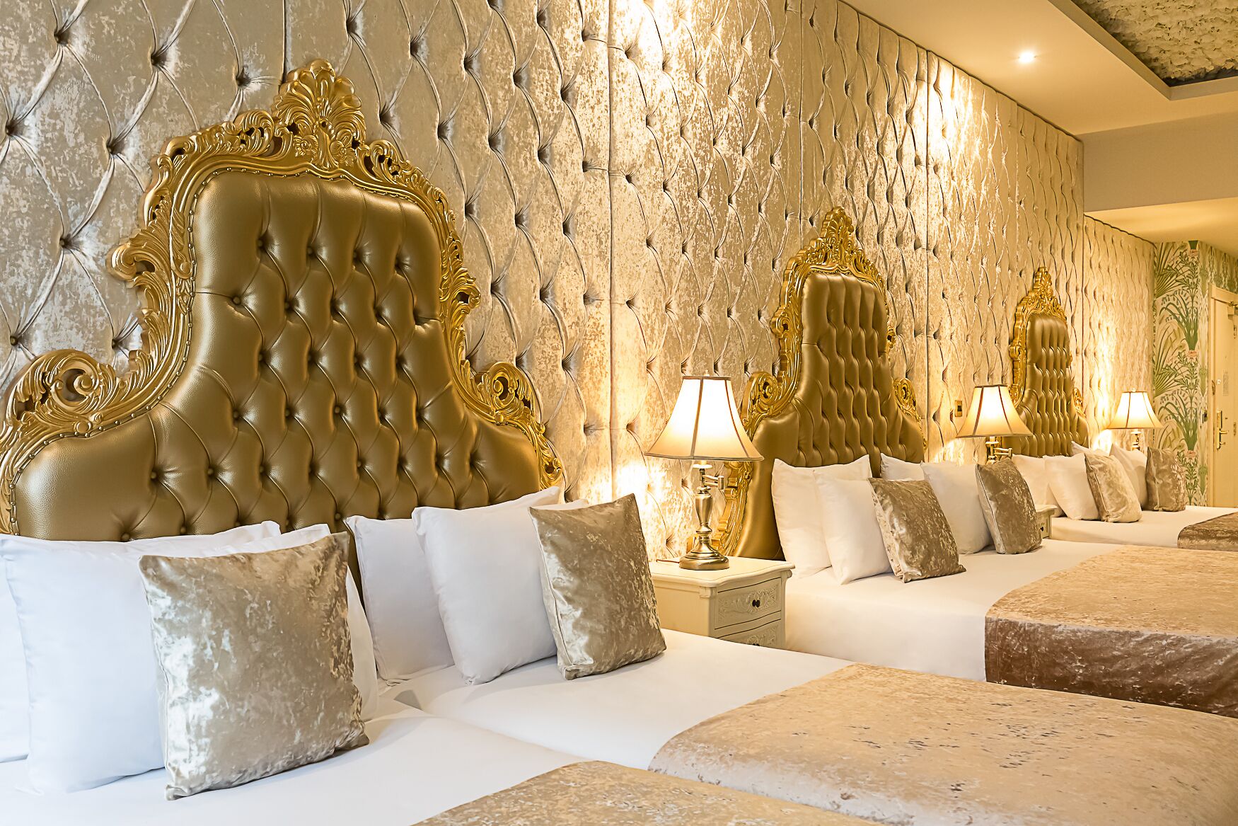 A luxurious hotel room with a tufted headboard, plush bedding, and a decorative wall.