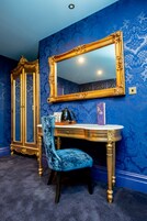 Una habitación con tocador, espejo y una silla azul.