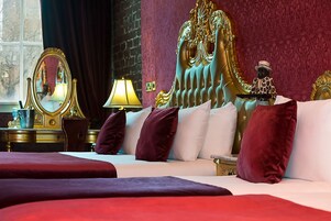 Una lujosa habitación de hotel con una cama grande, un cabecero dorado y un espejo.