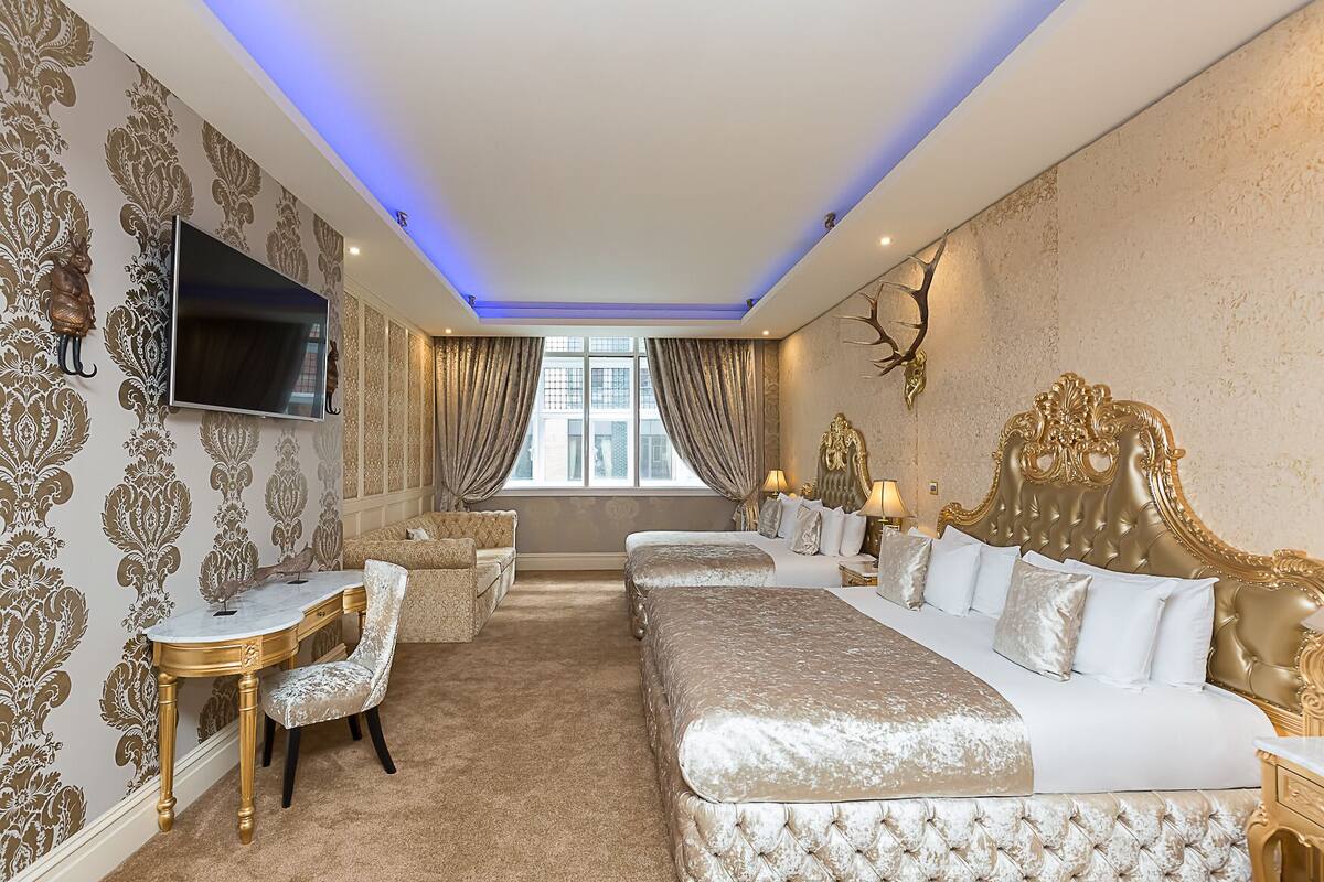 A luxurious bedroom with a large bed, a sofa, a desk, and a TV.