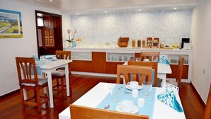 A dining area with wooden chairs and a table set for two, a kitchen counter with various items, and a view of a landscape through a door. - Hotel Drago San Antonio (Icod de los Vinos)