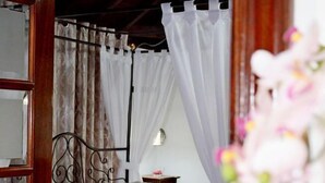 A bedroom with a bed, curtains, and a nightstand. - Hotel Drago San Antonio (Icod de los Vinos)