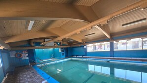 An indoor swimming pool with clear water, marked lanes, and a tiled floor. - Camelot Court Motel (Prince George)