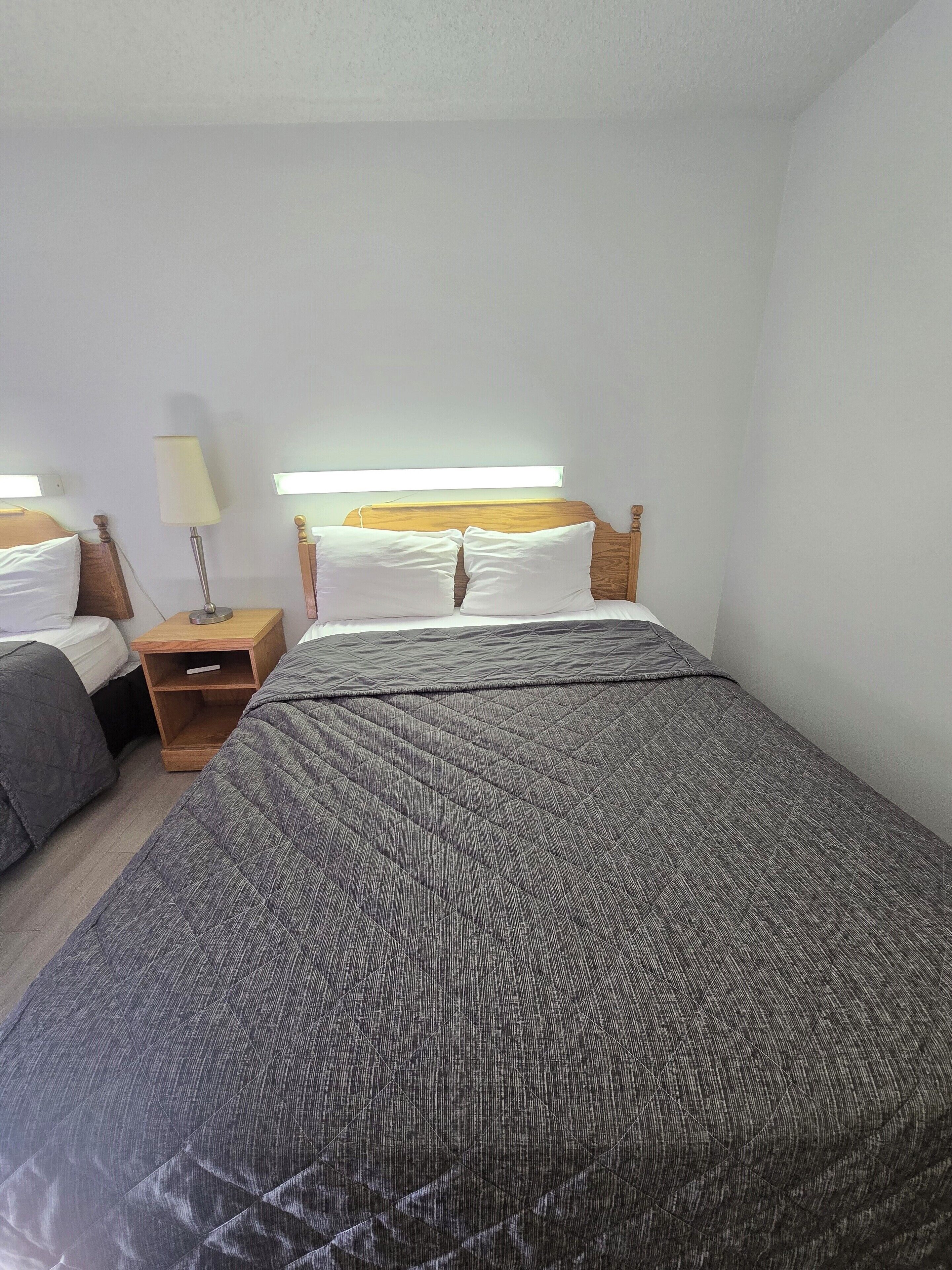 Una habitación de hotel con una cama grande, dos mesitas de noche y una lámpara de pared.