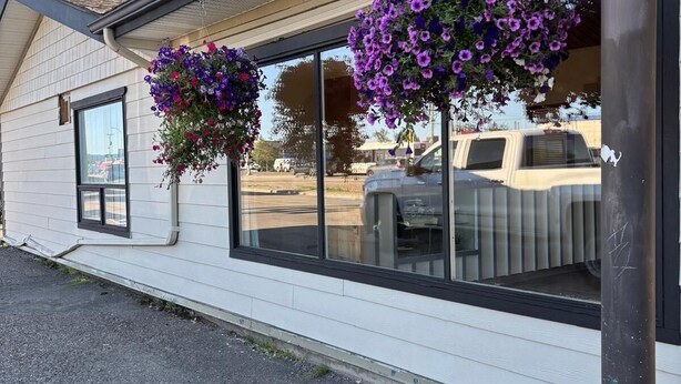 Motel amb grans finestres i cistelles florals penjants.