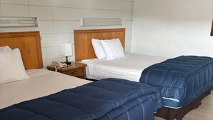 Habitació d'hotel amb dos llits, cadascun amb capçalera de fusta, roba de llit blanca i una taula de nit amb una làmpada i un telèfon.