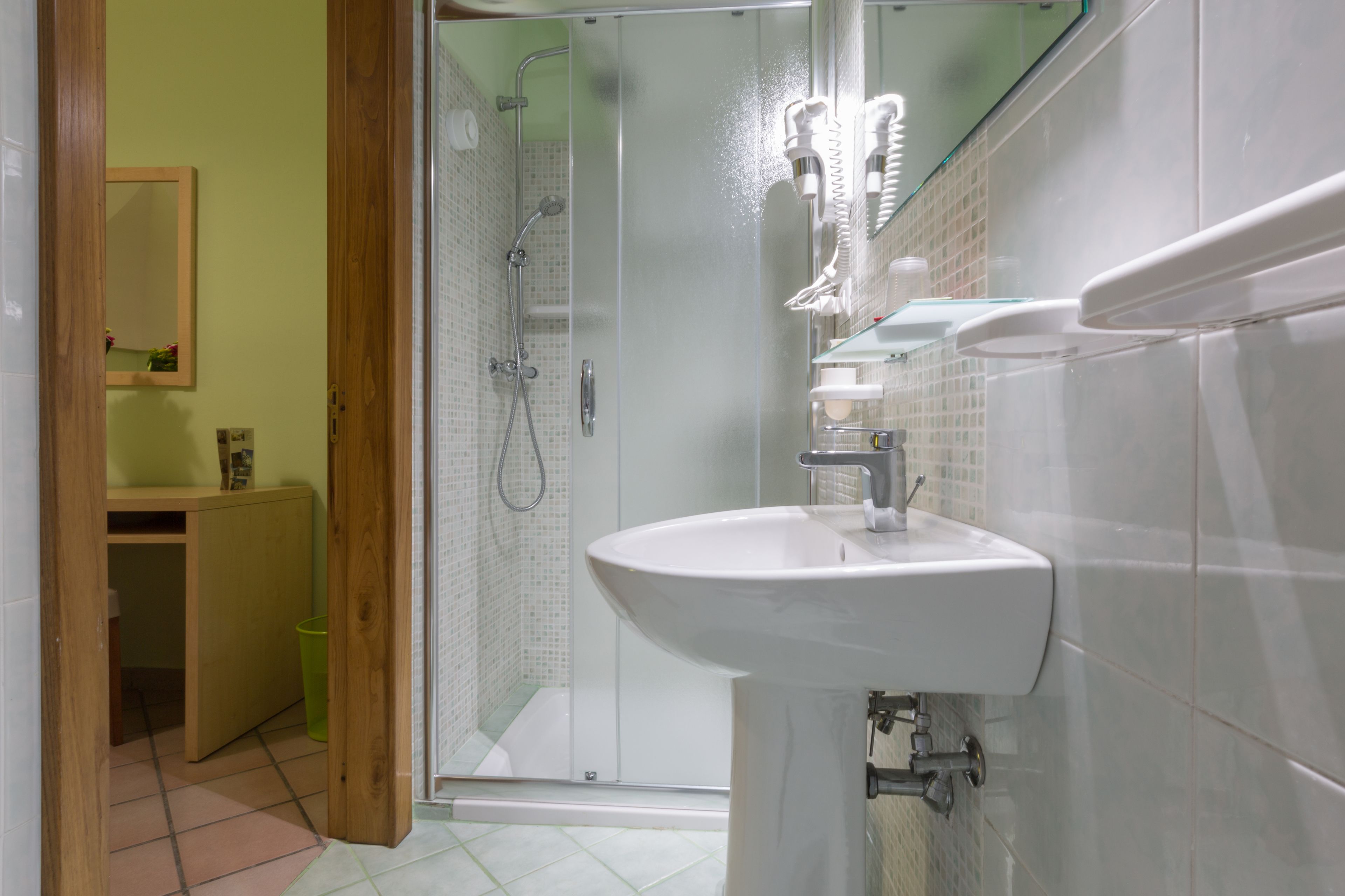 A modern bathroom with a glass shower enclosure, a white sink, and a wooden cabinet.