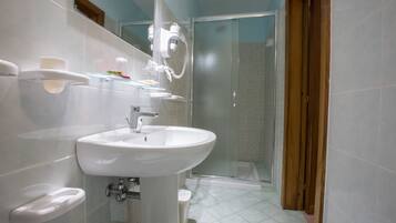 A bathroom with a white sink, toilet, and shower.