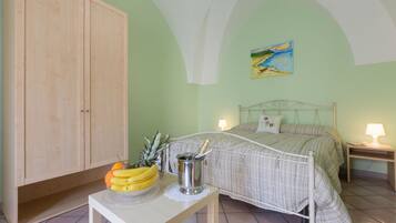 Camera da letto con un letto, lampade sui comodini, un armadio in legno e un tavolo con frutta e una bottiglia di champagne.