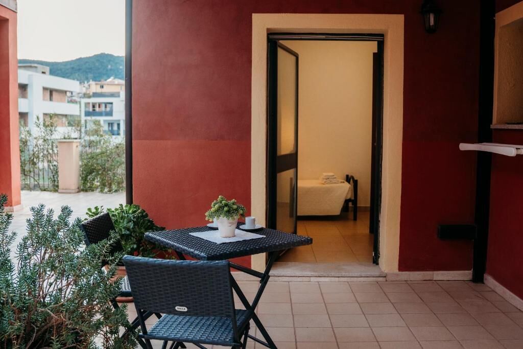 Ein Balkon mit Tisch, Stühlen, einer Topfpflanze und Blick auf ein Gebäude im Hintergrund.