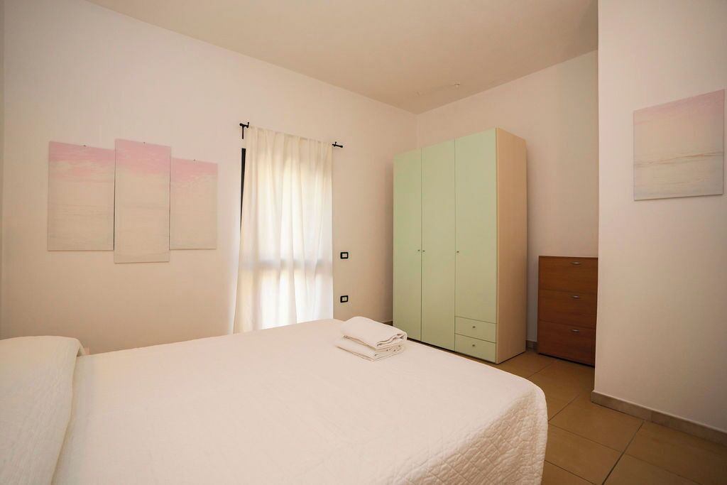 A bedroom with a bed, a wardrobe, and a small cabinet.