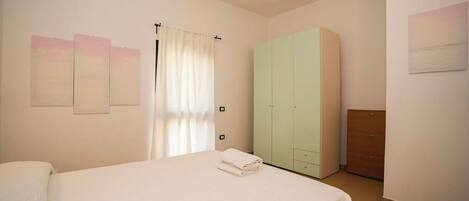 A bedroom with a bed, a wardrobe, and a small cabinet.