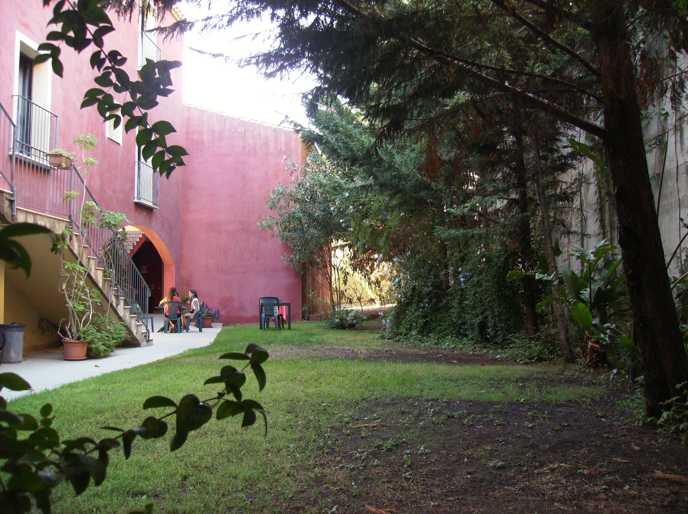 Um pátio com um edifício vermelho, uma escadaria e um pequeno espaço com assentos.