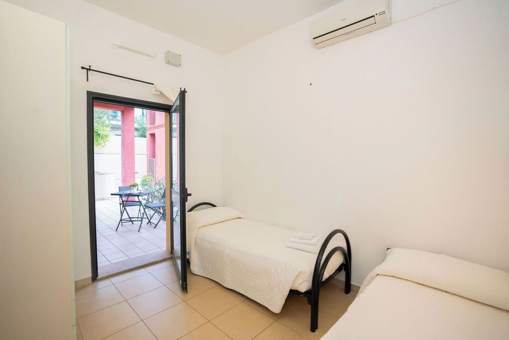 A small, clean room with a single bed, a chair, and a table.