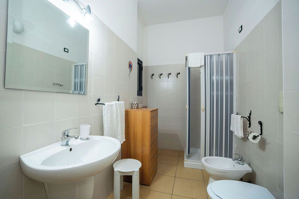 A bathroom with a large mirror, two sinks, a wooden cabinet, and a shower with a striped curtain.