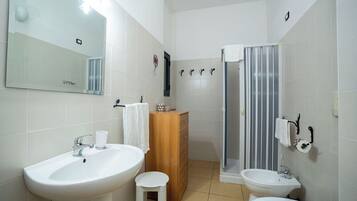 A bathroom with a large mirror, two sinks, a wooden cabinet, and a shower with a striped curtain.
