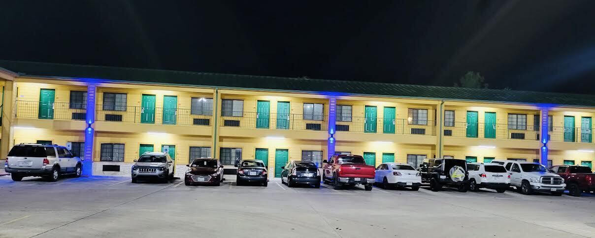 Un hotel de varios pisos con una fila de coches estacionados frente a él.