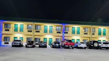 Un hotel de varios pisos con una fila de coches estacionados frente a él.