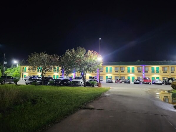 A parking lot with cars and a building with green shutters in the background.