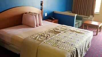 Habitación de hotel con una cama grande, un escritorio, una silla y un ventanal con cortinas.