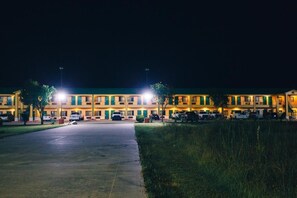 A multi-story hotel with a central courtyard, illuminated by street lamps.