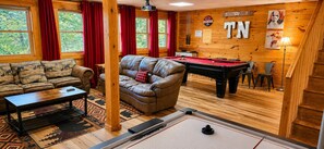 Una habitación acogedora con mesa de billar, un sofá de cuero y equipo de billard.