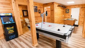 A wooden-floored room with a foosball table, a claw machine, and a small table tennis table.