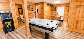 A wooden-floored room with a foosball table, a claw machine, and a small table tennis table.