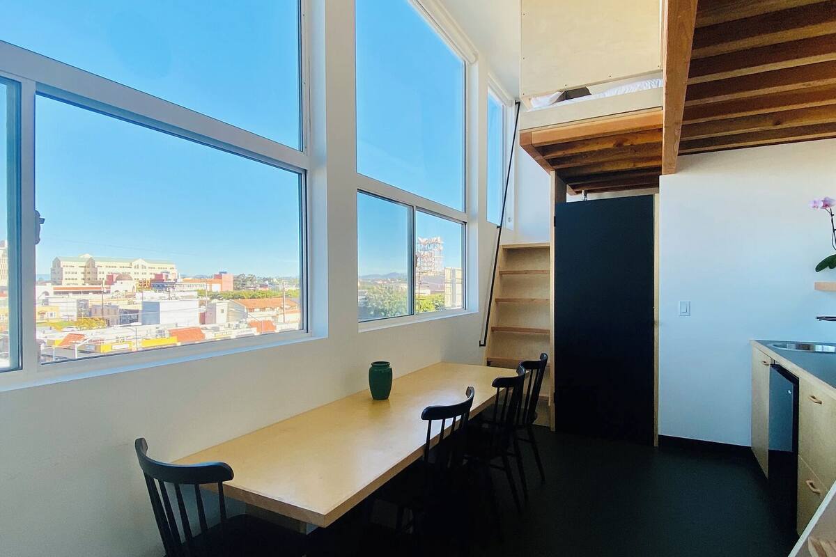 Quarto com uma janela grande, uma mesa de madeira e uma cadeira.
