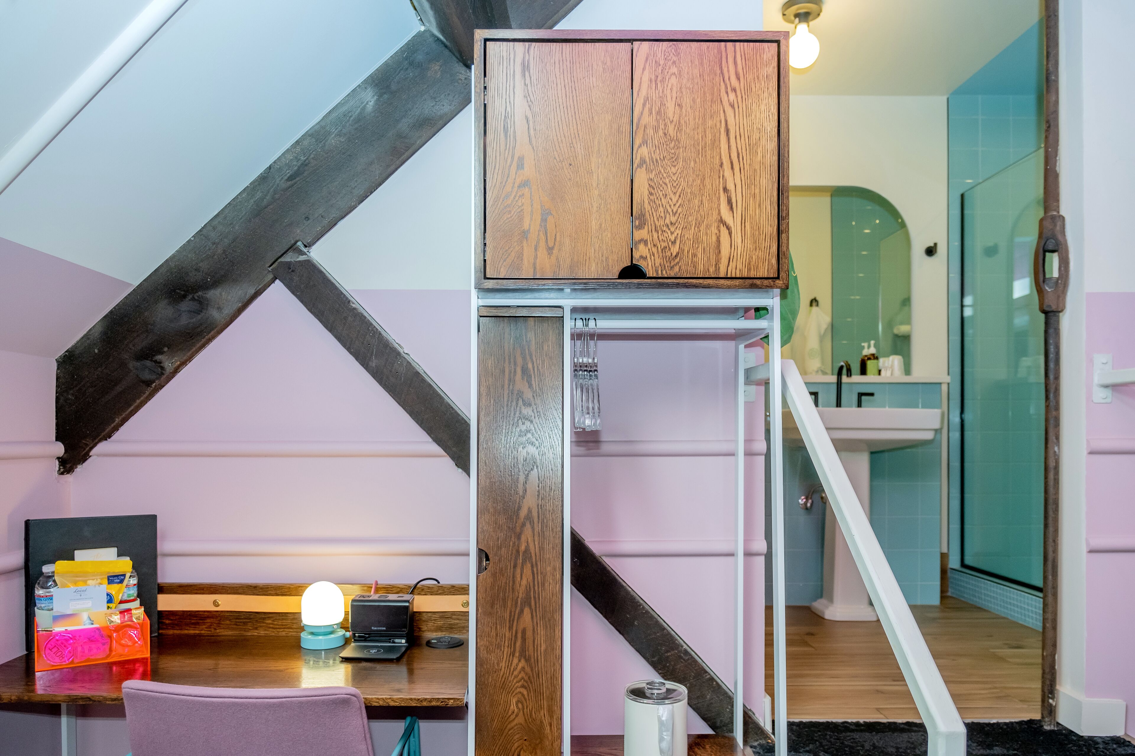 A compact kitchen with a wooden cabinet, a sink, and a staircase leading to a bathroom.