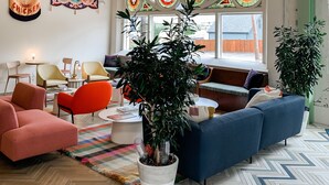 Una sala de estar moderna con un amplio ventanal de vitral, asientos cómodos y estandartes decorativos.