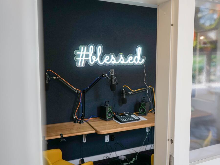 A recording studio with a neon sign reading "#blessed" and audio equipment.