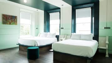 A modern hotel room with two beds, a bench, and large windows.