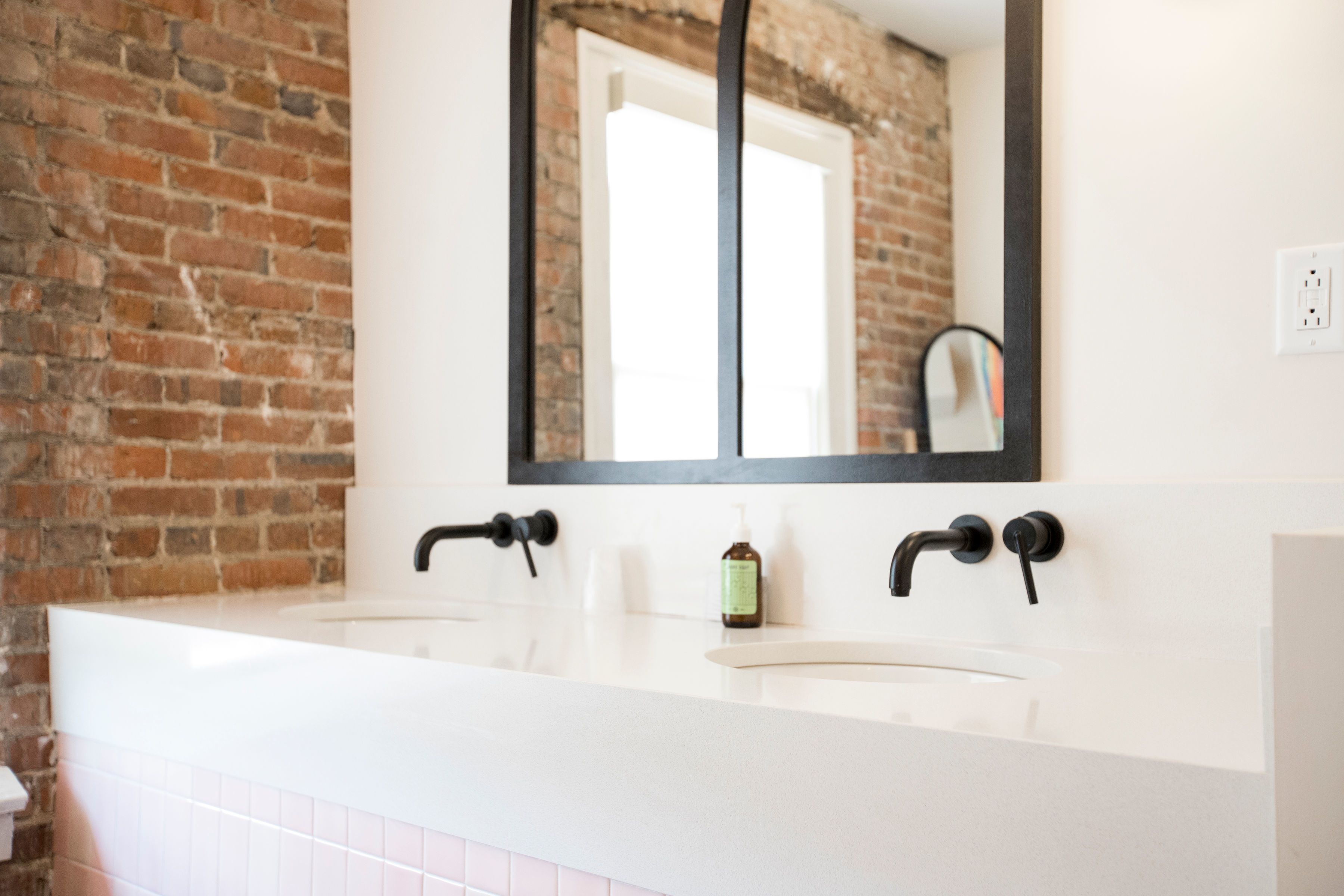 A bathroom with a white sink, black faucets, and a mirror above it.