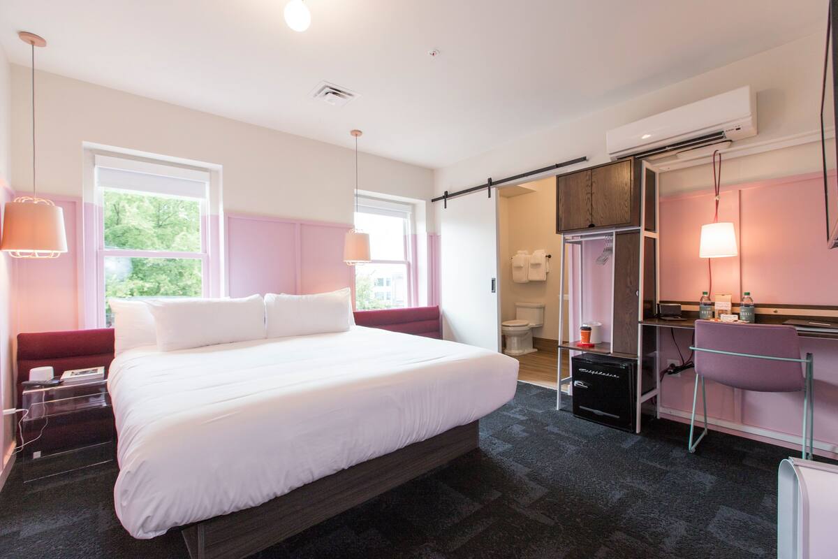 Ein modernes Hotelzimmer mit einem großen Bett, einem Schreibtisch und einem Badezimmer.