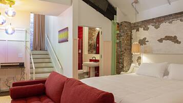 Un dormitorio con una cama grande, un sofá rojo, una escalera y un baño con un lavamanos rojo.