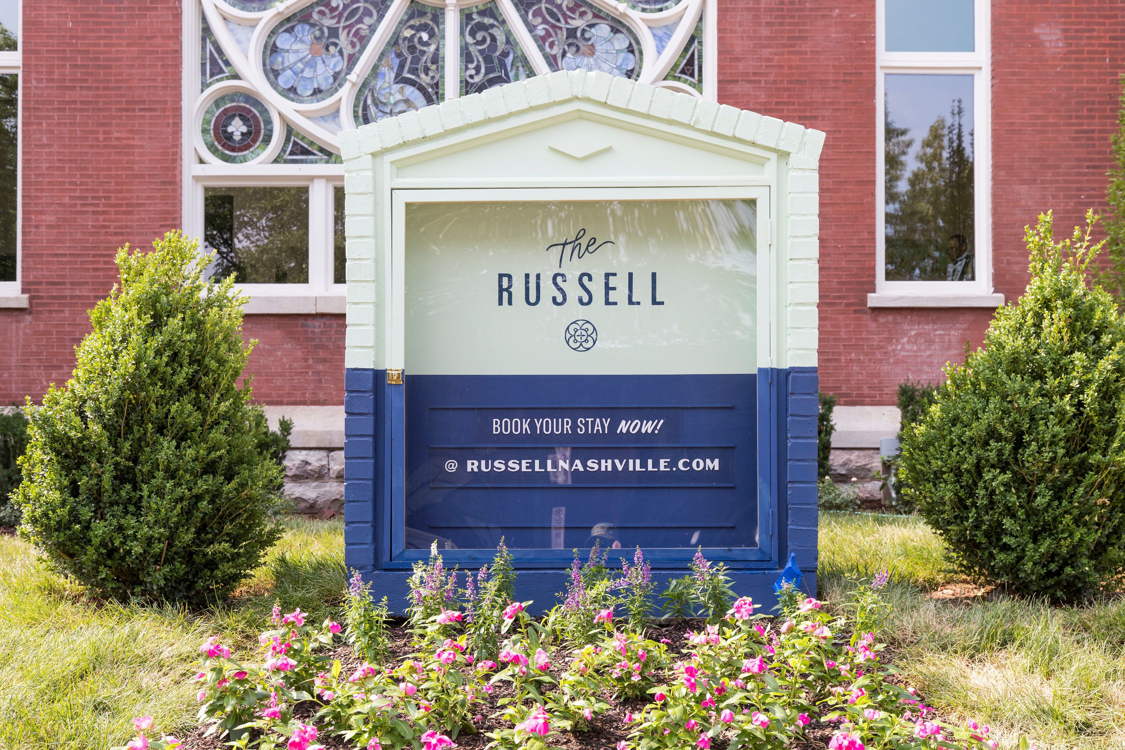 Een bord voor Hotel The Russell met een melding om te reserveren en een website-URL.